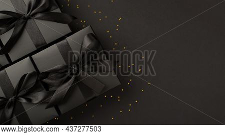 Top View Photo Of Stylish Black Gift Boxes With Black Satin Ribbon Bow Tag And Golden Confetti On Is