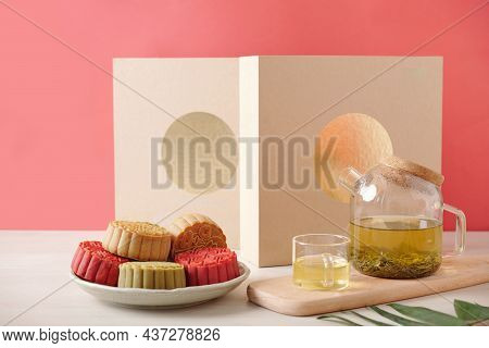 Transparent Pot Of Green Tea And Plate Of Colorful Mooncakes With Verious Fillings Served For Dinner