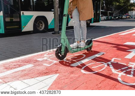 traffic, city transport and people concept - woman riding electric scooter along red bike lane with signs of bicycles and two way arrows on street