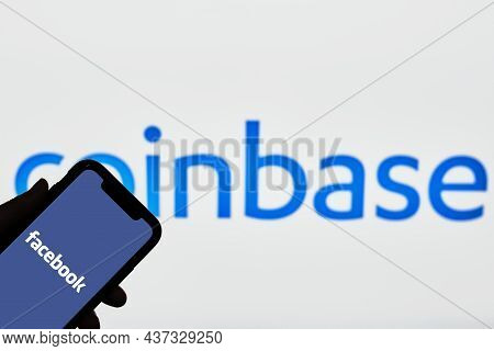 Tashkent, Uzbekistan - 22 October, 2021: Hand Holds Mobile Phone With Facebook Logo Over Coinbase Lo