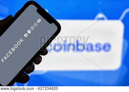 Tashkent, Uzbekistan - 22 October, 2021: Hand Holds Mobile Phone With Facebook Logo Over Coinbase Lo