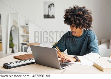 Portrait Of Male African-american Student Using Laptop While Doing Homework In College Dorm, Copy Sp