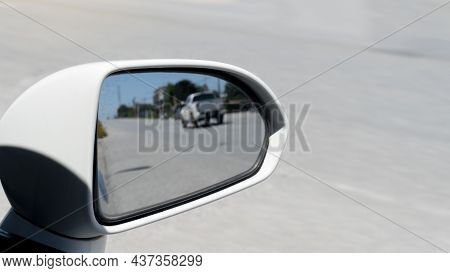 Traffic From Behind Through The Mirrors Wing Of A White Car. With Blurred Of Other Cars Drving On Th