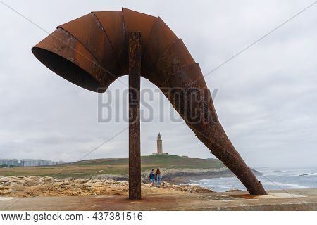 A Coruna, Spain, August 14, 2021. Sculpture Of The Caracola And In The Background The Tower Of Hercu