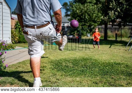 Playing Kickball With Grandpa In The Backyard