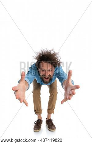 handsome casual man leaning forward and grabbing something on white background