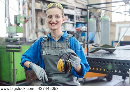 Woman worker in metal factory showing protective workwear