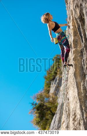 The Girl Climbs The Rock. The Climber Trains On Natural Terrain.  A Woman Overcomes A Difficult Clim