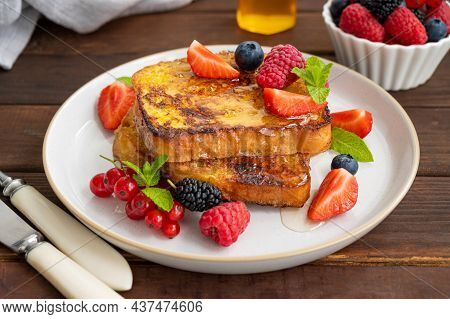 A Stack Of French Toast On A Plate With Fresh Berries, Almond Petals And Honey On A Dark Wooden Back