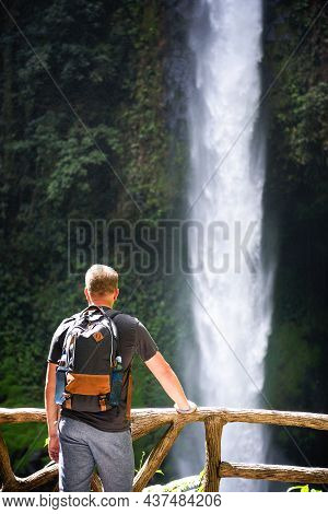 Tourist Looking At The La Fortuna Waterfall In Costa Rica. The Waterfall Is Located On The Arenal Ri