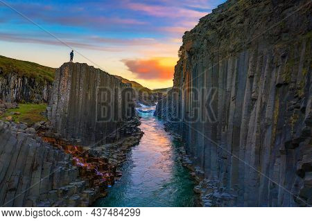 Hiker Standing At The Top Of Studlagil Canyon With The Jokulsa A Bru River In East Iceland At Sunset