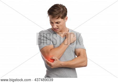 Sad Young Caucasian Guy Athlete Suffering From Elbow Pain, Presses Hand To Sore Spot, Shown In Red