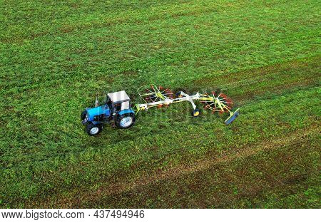 Tractor Raking Grass For Silage Harvesting. Agriculture Machinery Working At Field. Grass Silage For