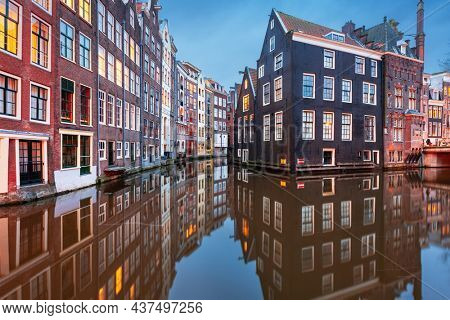 Amsterdam, Netherlands with narrow canals and buildings lining them in the morning time.