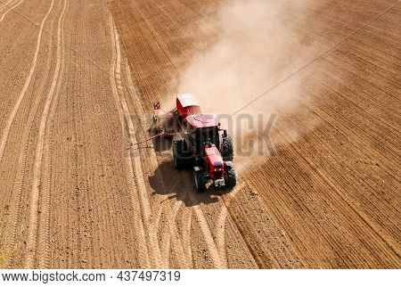 Agricultural Tractor Sowing Seed Onto At Field. Farming And Seeding Concept. Seeds Sowing In Farmers