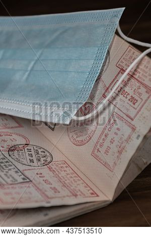 Closeup Of An Open Passport With Different Stamps And A Face Mask