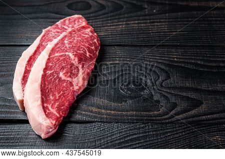 Raw Rump Steak Or Top Sirloin Cap Beef Meat Steaks On Butcher Table. Black Wooden Background. Top Vi