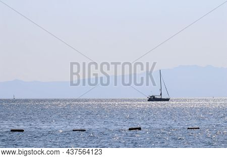 Blue Sea Waves Sparkling In The Sun And A Yacht.
