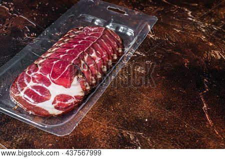 Italian Sliced Cured Coppa Meat In Vacuum Packaging. Dark Background. Top View. Copy Space