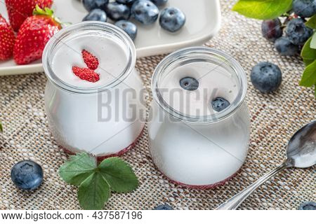 Two glass containers with plain yoghurt and berries on the table.   Light summer mood.