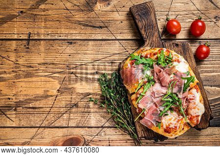 Sliced Pizza With Prosciutto Parma Ham, Arugula And Parmesan Cheese On A Wooden Board. Wooden Backgr