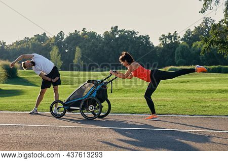 Active Family With A Child Doing Exercises And Fitness In The Morning Outdoor. Running With A Joggin