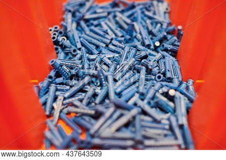 Dowels Wall Plugs Close Up. Plastic Blue Dowels On Red Background, Dowels For Fixation And Installat
