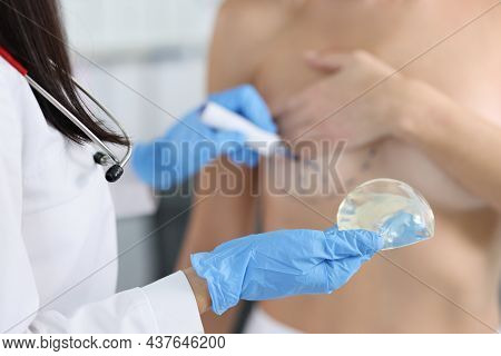 Plastic Surgeon Holding Silicone Breast Implant And Applying Preoperative Markings To Patient Chest 