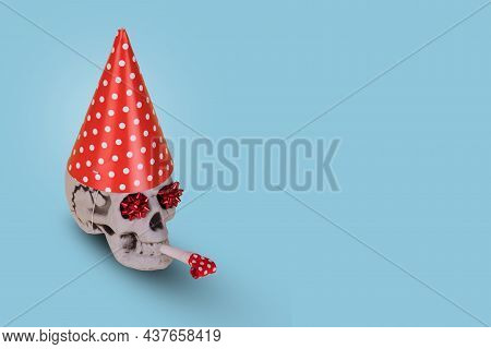 Creative Halloween Idea With Human Skull  With A Red Birthday Cap And Whistle  Isolated On A Blue Ba