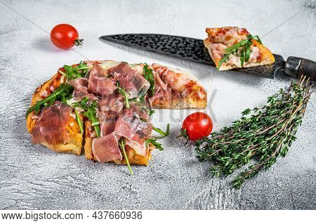 Italian Pizza With Parma Ham, Arugula And Cheeseon A Kitchen Table. White Background. Top View