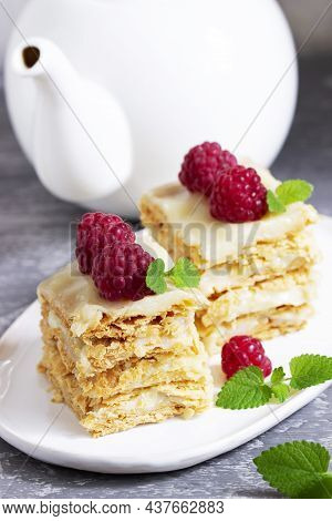 Pieces Of Napoleon Cake Decorated With Raspberries And Lemon Balm Leaves On A Light Background.