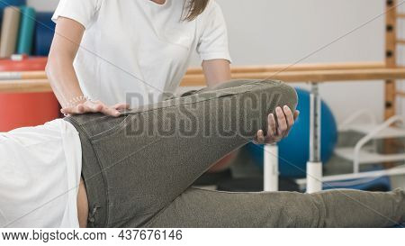 Female Physiotherapist Doing Leg And Hip Stretching Treatment On A Male Patient.