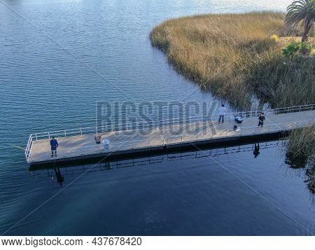 Aerial View Of Wood Pier With Fishers And Their Fishing Rods Trying To Catch Fish At The Miramar Lak