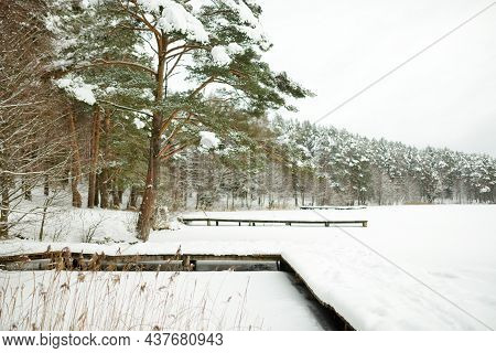 Beautiful View Of Ice Covered Balzis Lake. Snowy Pine Forests Surrounding A Small Lake. Winter Lands