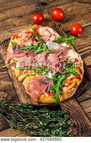 Sliced Pizza With Prosciutto Parma Ham, Arugula And Parmesan Cheese On A Wooden Board. Wooden Backgr