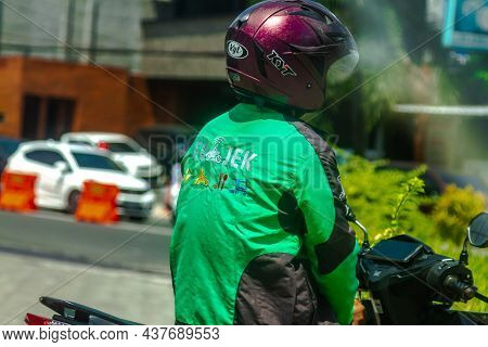 An online motorcycle taxi driver with a cellphone is placed on the dashboard of a motorcycle. SLEMAN, INDONESIA - OCTOBER 20, 2021.