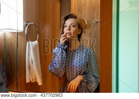 Portrait Of Young Beautiful Woman In Dress Doing Make-up, Touch Her Lips Standing Near Mirror In The