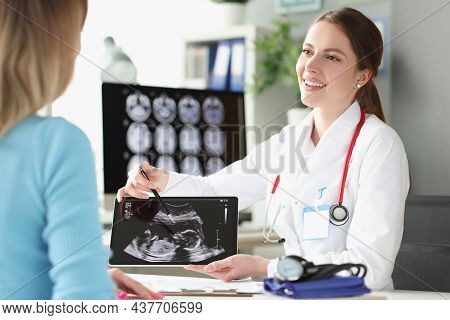 Portrait Of Smiling Gynecologist Holding Ultrasound Picture And Showing Little Child To Happy Mother