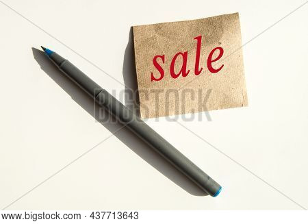 The Word Sale Is Written On Brown Wrapping Paper, There Is A Pen Next To It