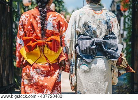 Rear View Of Two Japanese Women Wearing Yukata Dress While Walking In Town. A Japanese Yukata Is A L
