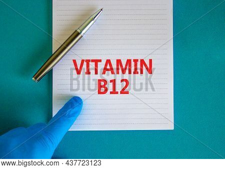 Vitamin B12 Symbol. White Note With Words Vitamin B12, Beautiful Blue Background, Doctor Hand In Blu