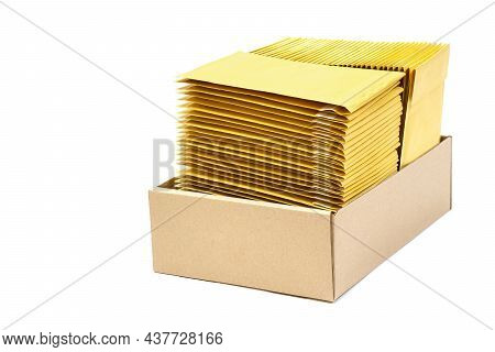 Two Stacks Of Jiffy Bags In A Kraft Cardboard Box Isolated On White. Standard Bubble Wrap Envelopes.