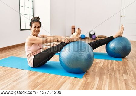 Mature hispanic couple doing excersice and stretching at yoga room. Two adult people doing pilates and flexibility workout