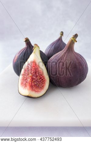 Closeup Of Three Whole And A Quarter Fig On White Marble Board With Copy Space. Straight On View. Se