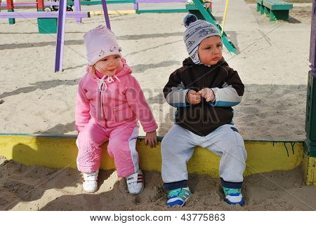 A Boy And Girl Sitting In A Sandbox