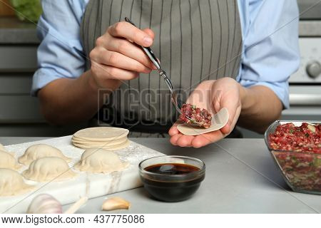 Woman Putting Gyoza Filling In Center Of Dough Wrapper At Light Grey Table, Closeup