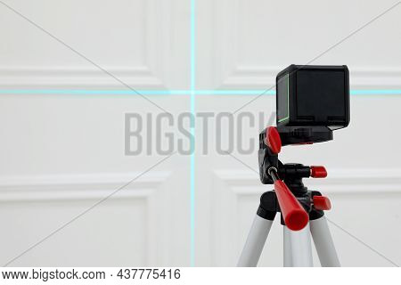 Cross Line Laser Level On Tripod In Front Of White Wall