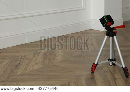 Cross Line Laser Level With Tripod On Wooden Floor Indoors