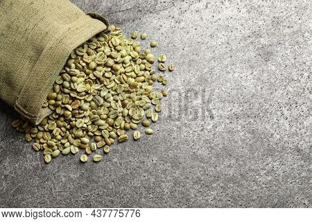Overturned Sackcloth Bag With Green Coffee Beans On Grey Table, Flat Lay. Space For Text