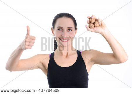 Young Strong Woman Holding Walnuts In Her Hands And Showing Ok Gesture